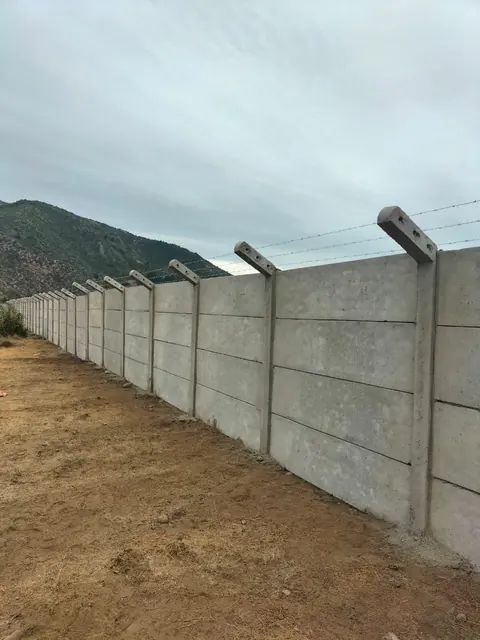 Cierre de hormigón con postes inclinados y alambre en terreno abierto