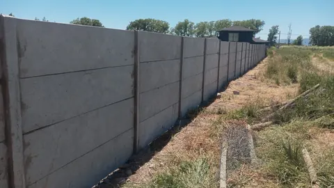 Cierre perimetral de hormigón junto a terreno con vegetación