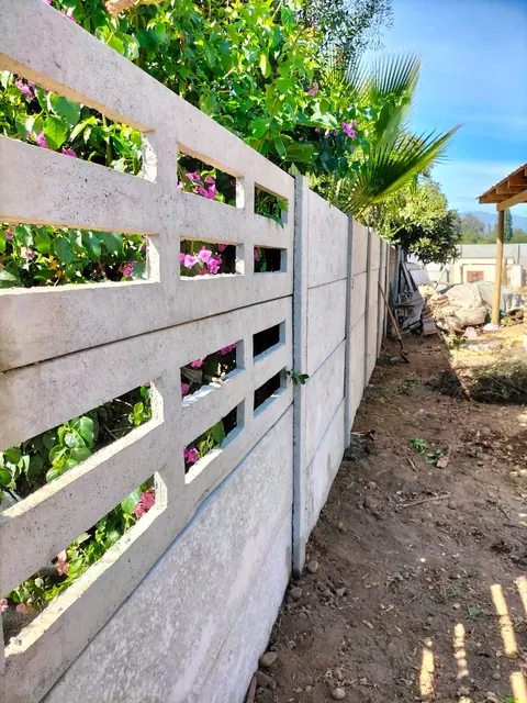 Cierre residencial con celosías de hormigón y plantas